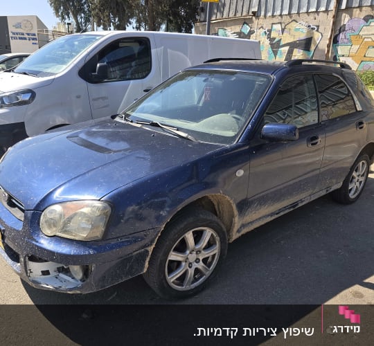 רכב כחול חונה ליד קיר עם גרפיטי